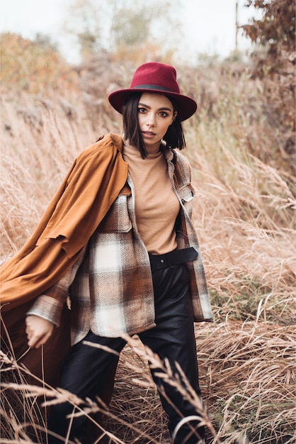 Jeune femme marche dans l'herbe sèche à l'automne