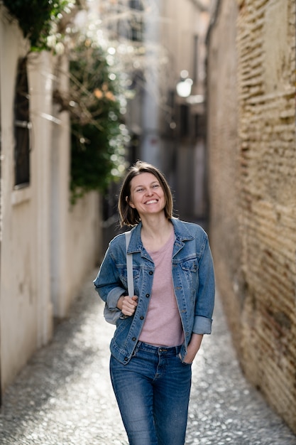 Une jeune femme marche heureuse dans la rue. Fille de tourisme caucasien visitant la vieille ville.