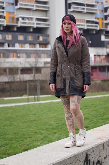 Photo une jeune femme marche sur un mur de soutènement sur la pelouse de la ville.