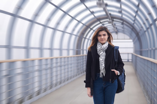 La jeune femme marche rapidement par le passage supérieur pour piétons couvert