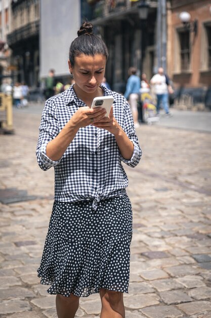 Une jeune femme marche avec un smartphone dans la ville