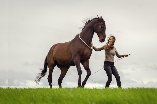 Une jeune femme marche avec son cheval.