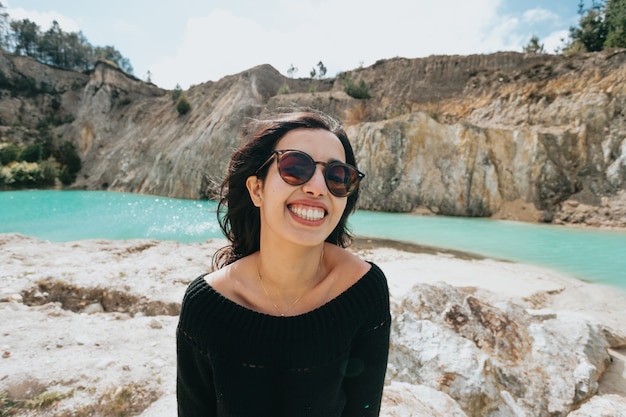 Jeune femme marocaine avec des lunettes de soleil sur un lac tropical aux eaux cristallines, concept de vacances et de vacances