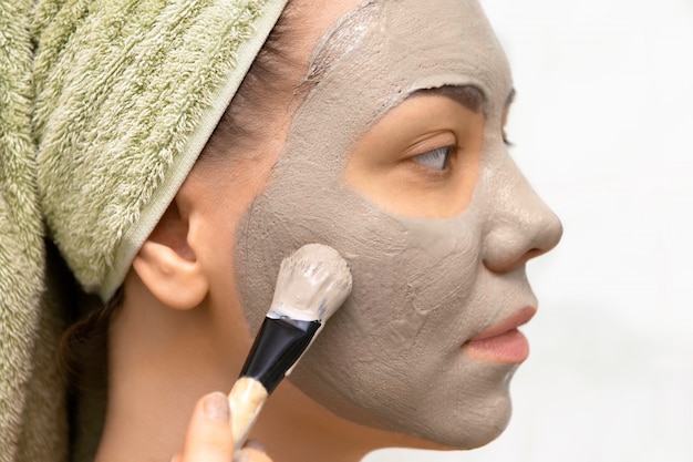 Jeune femme avec masque facial à l'argile.