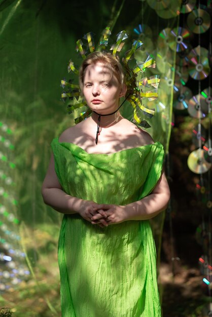 Photo une jeune femme avec un masque en miroir et un tissu au néon se tient dans la forêt devant le décor d'un boîtier de cd