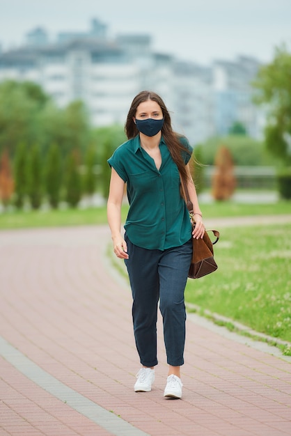 Jeune femme avec un masque noir dans le parc