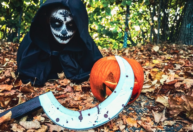 Jeune femme avec un masque de peinture halloween portant une capuche noire