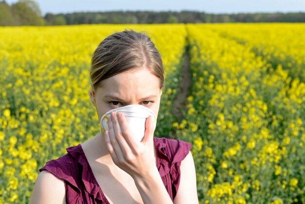 Une jeune femme avec un masque de pollution debout dans un champ