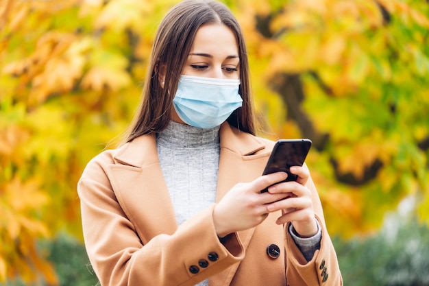 Jeune femme avec un masque de protection dans le parc de l'automne