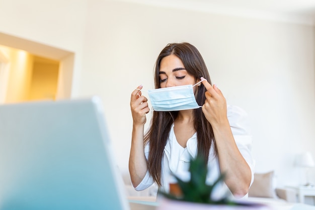 Jeune femme avec masque de protection travaillant à domicile