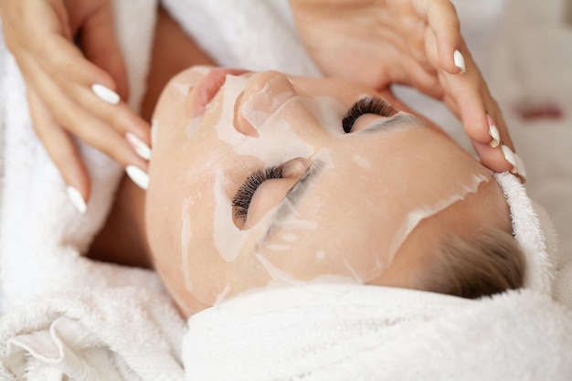 Jeune femme avec un masque en tissu au salon spa