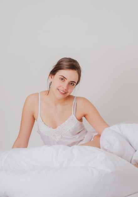 Jeune femme le matin après un bon sommeil dans un lit confortable blanc fille allongée sur des oreillers moelleux éveillé