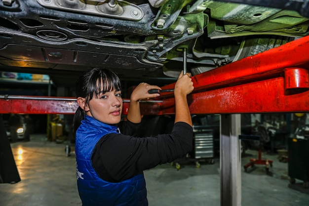 Jeune femme mécanicienne travaillant sur la réparation d'un moteur de voiture