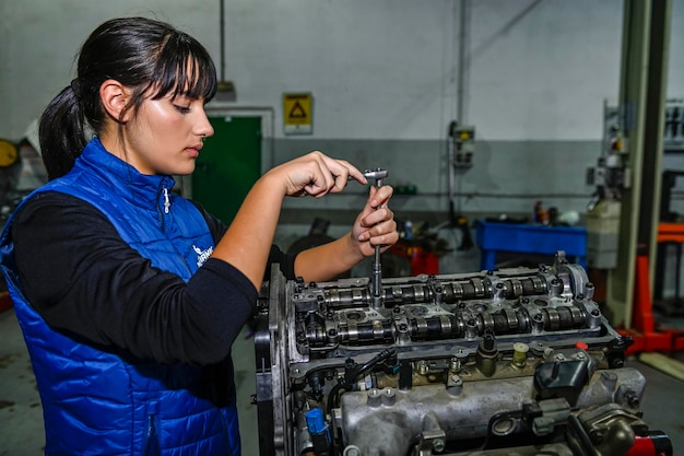 Jeune femme mécanicienne travaillant sur la réparation d'un moteur de voiture