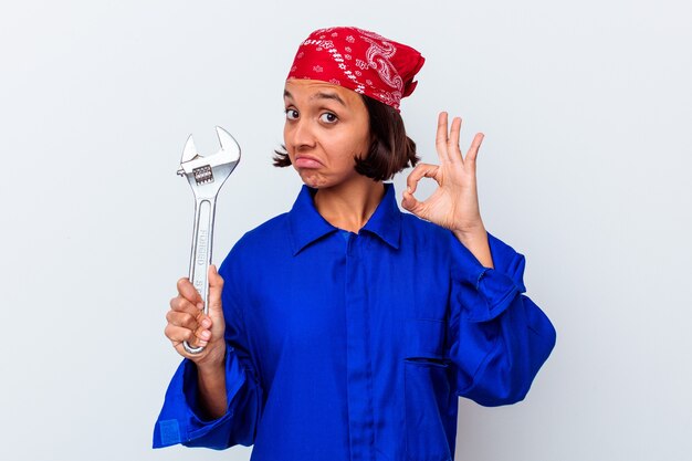 Jeune femme mécanique tenant une clé isolée joyeuse et confiante montrant le geste ok.