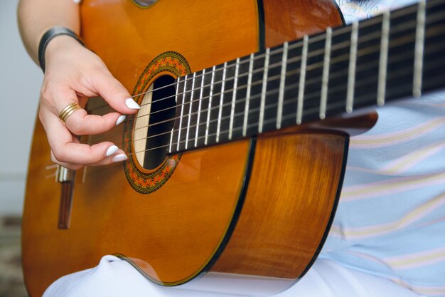jeune femme méconnaissable jouant de la guitare acoustique se concentre sur la main sur les cordes au trou de son de la guitare