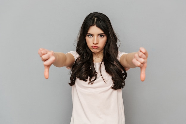 Jeune femme mécontente debout isolé montrant les pouces vers le bas.