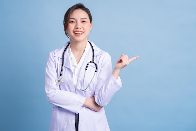 Jeune femme médecin asiatique debout sur fond bleu