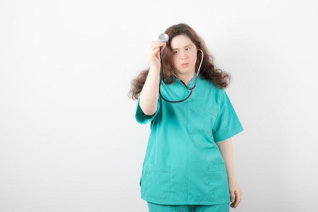 Jeune femme médecin atteinte du syndrome de Down à l'aide d'un stéthoscope sur un mur blanc