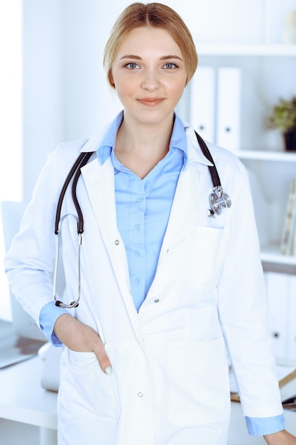 Jeune femme médecin au travail à l'hôpital en regardant la caméra. Le chemisier de thérapeute de couleur kaki a fière allure. Concept de médecine et de soins de santé.