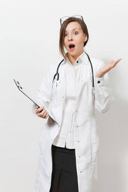 Jeune femme médecin bouleversée choquée avec stéthoscope, lunettes isolées sur fond blanc. Femme médecin en blouse médicale tenant une carte de santé sur le dossier du bloc-notes. Personnel de santé, concept de médecine.