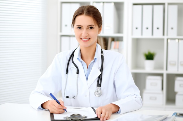 Jeune femme médecin brune assise à la table et travaillant au bureau de l'hôpital