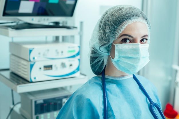 Jeune femme médecin debout dans la salle d'opération avec un équipement moderne derrière son dos