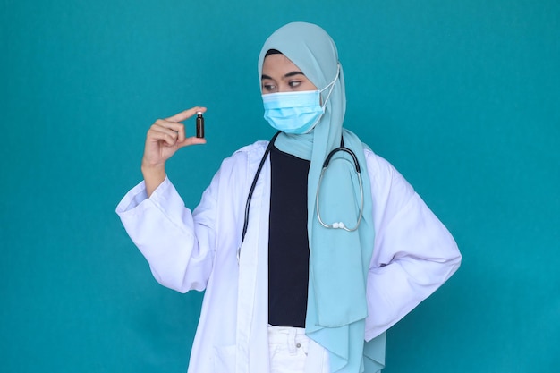 Une jeune femme médecin hijab tient une bouteille de médicament pour injection. Flacon en verre médical pour la vaccination.