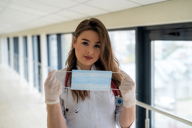 Jeune femme médecin ou infirmière mettant un masque pour se protéger contre le coronavirus COVID-19