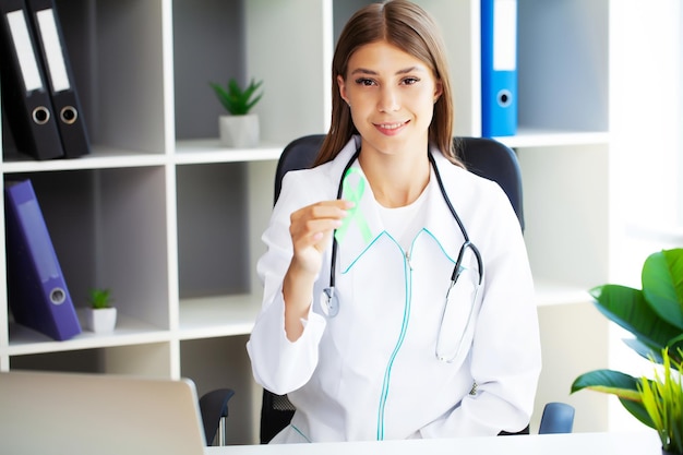 Jeune femme médecin montrant un ruban vert comme symbole de sensibilisation au cancer du lymphome