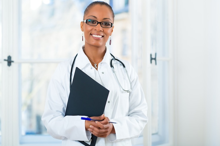 Photo jeune femme médecin noir debout à une fenêtre en clinique avec un fichier ou un dossier