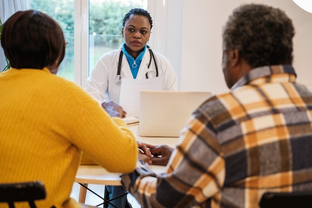 Jeune femme médecin passant la consultation à deux personnes âgées et leur donnant le diagnostic de leurs maladies Concept d'urgence en médecine de soins de santé