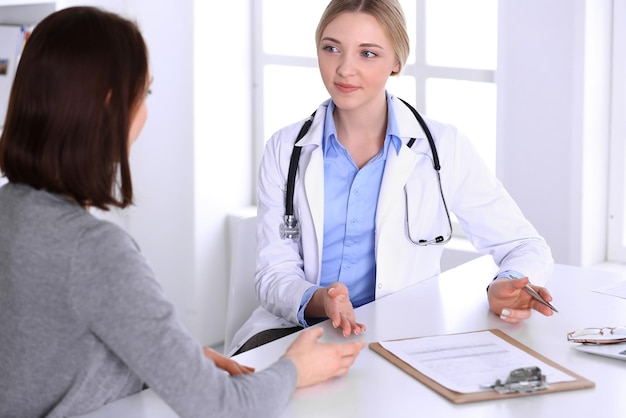 Jeune femme médecin et patiente lors d'un examen médical au bureau de l'hôpital. Le chemisier de couleur bleue du thérapeute a l'air bien. Concept de médecine et de soins de santé.