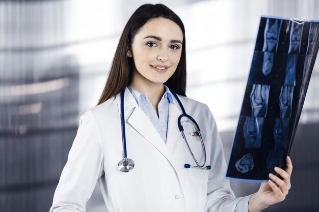 Une jeune femme médecin professionnelle regarde le radiogramme de son patient. Médecin au travail dans le bureau d'une clinique. Notion de médecine.