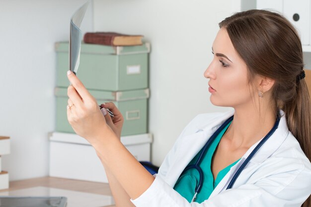Jeune femme médecin regardant l'image aux rayons x des poumons
