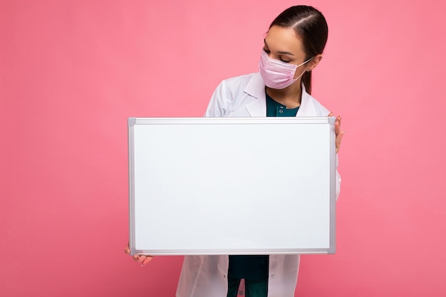 Jeune femme médecin séduisante en masque protecteur et blouse médicale blanche tenant un vide