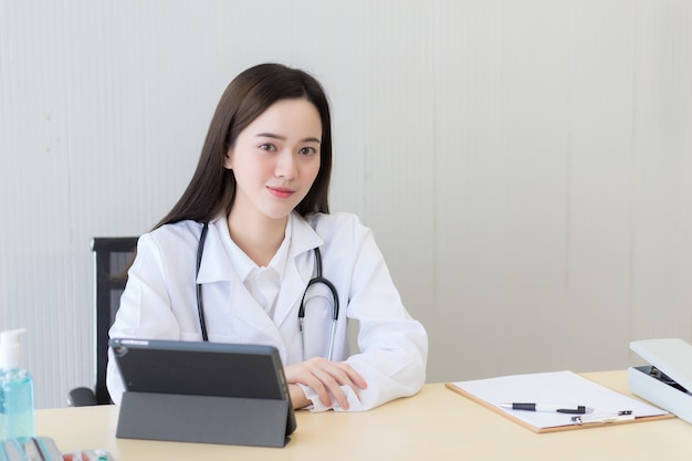 Jeune femme médecin souriante professionnelle asiatique assise au bureau à l'hôpital