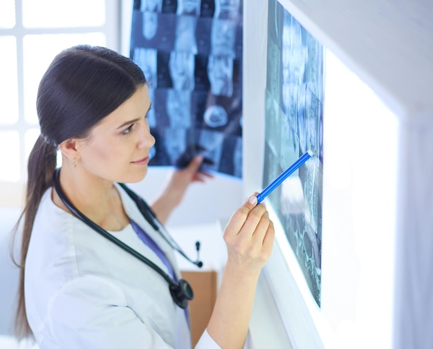 Jeune femme médecin souriante avec stéthoscope pointant sur Xray au cabinet du médecin