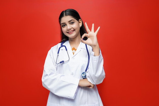 Jeune femme médecin avec sourire portant manteau et stéthoscope autour du cou indien pakistanais