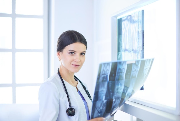 Jeune femme médecin avec stéthoscope examinant la radiographie au cabinet du médecin