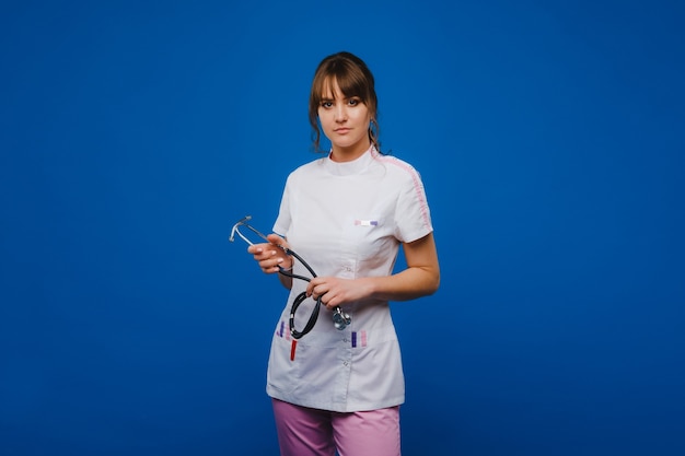 Jeune femme médecin avec stéthoscope isolé sur fond bleu.