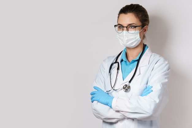 Jeune femme médecin avec un stéthoscope sur mur gris