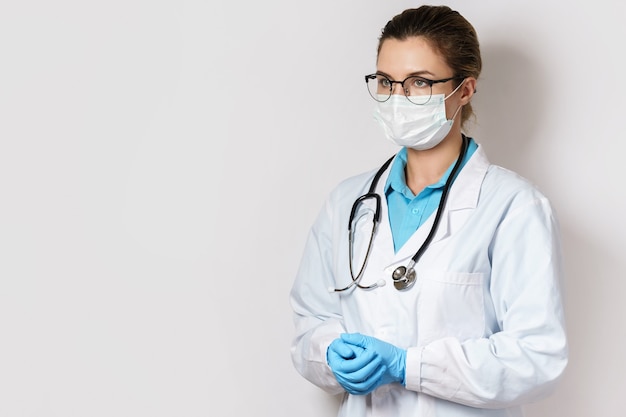 Jeune femme médecin avec un stéthoscope sur mur gris