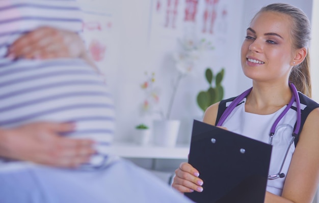 Photo jeune femme médecin avec stéthoscope et tablette parlant avec une femme enceinte à l'hôpital