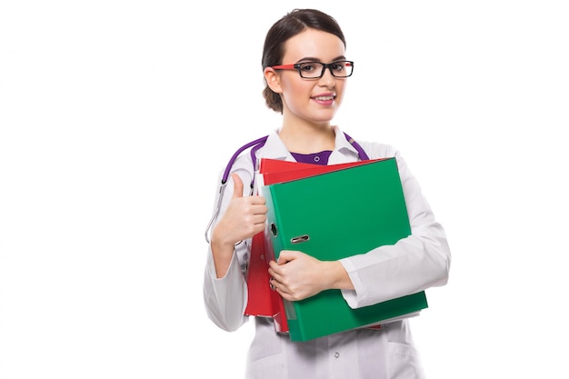 Jeune, femme médecin, à, stéthoscope, tenue, relieurs, dans, elle, mains, à, pouce haut, dans, blanc, uniforme, sur, blanc