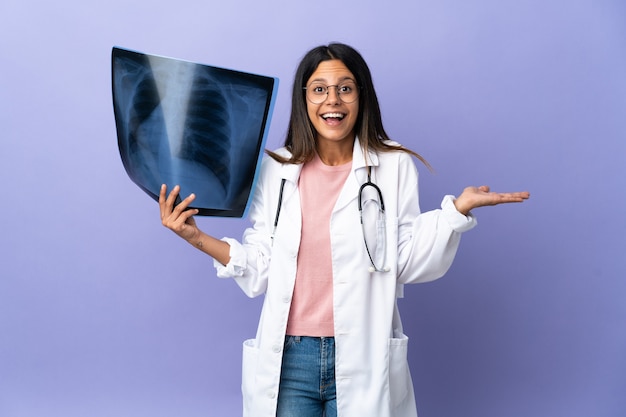 Jeune femme médecin tenant une radiographie avec une expression faciale choquée