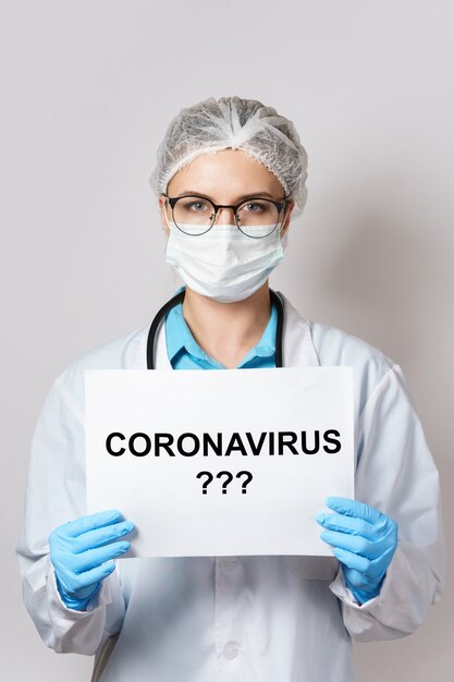 Une jeune femme médecin tient du papier avec le lettrage CORONAVIRUS