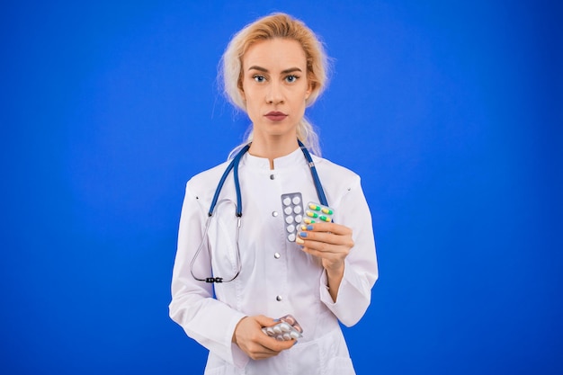 Une jeune femme médecin tient des pilules dans ses mains sur un fond bleu