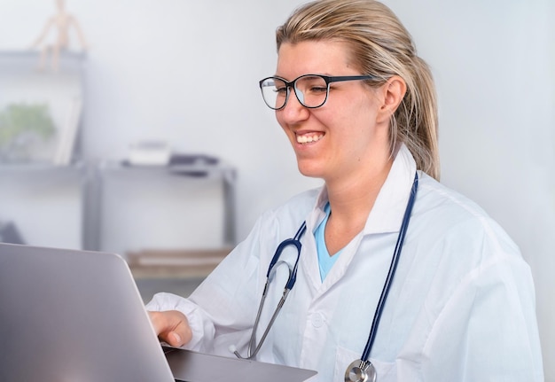 Jeune femme médecin travaillant sur ordinateur au bureau