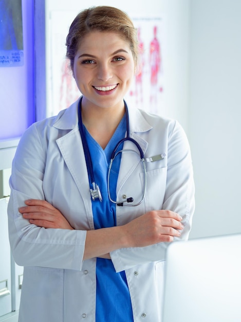 Jeune femme médecin en uniforme blanc debout dans le bureau des cliniques